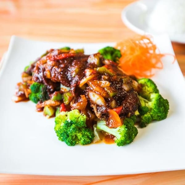 Nisa Thai Asian Cuisine's stir-fried dish with dark sauce, broccoli, and shredded carrots on a white plate.