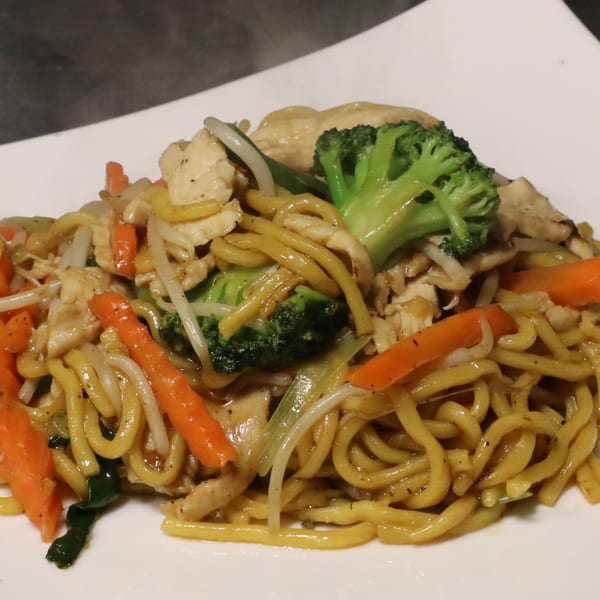 Chicken lo mein with broccoli, carrots, and bean sprouts on a white plate.