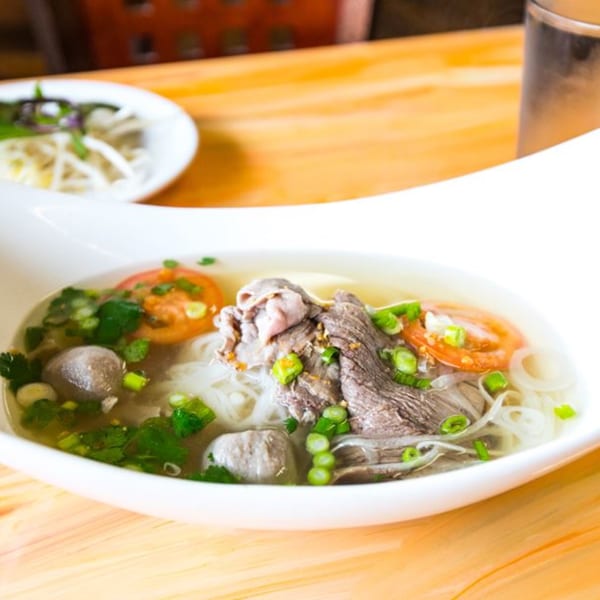 A bowl of Nisa Thai Asian Cuisine's pho with beef, meatballs, noodles, and fresh vegetables.