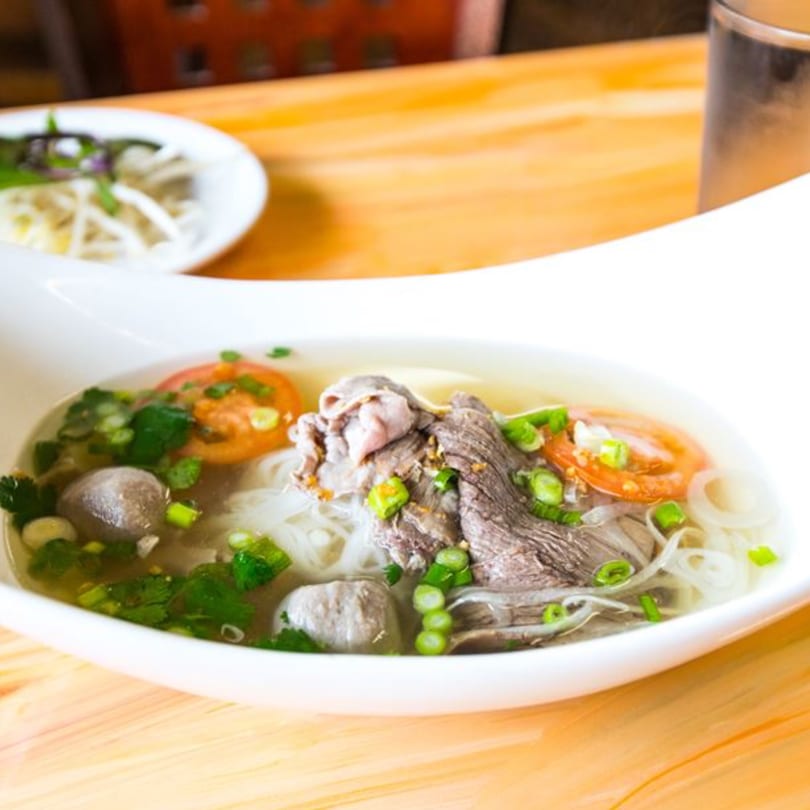 A bowl of Nisa Thai Asian Cuisine's pho with beef, meatballs, noodles, and fresh vegetables.